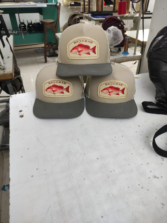 Tres gorras trucker beige con parche de pargo cubera y visera gris oliva